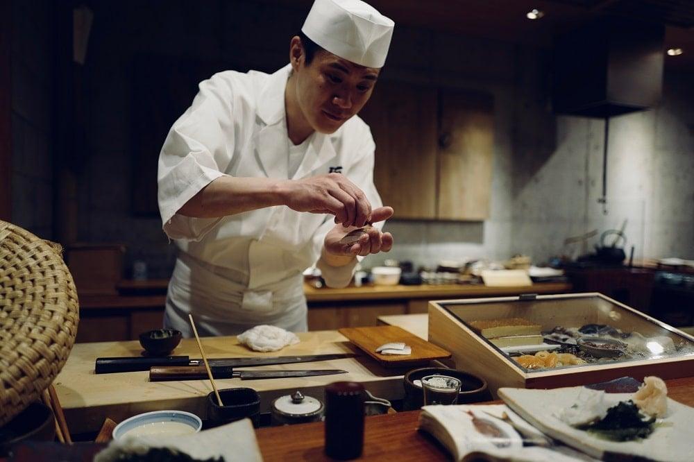 Seorang chef yang sekaligus pemilik binis kuliner ini sedang membuat sushi.